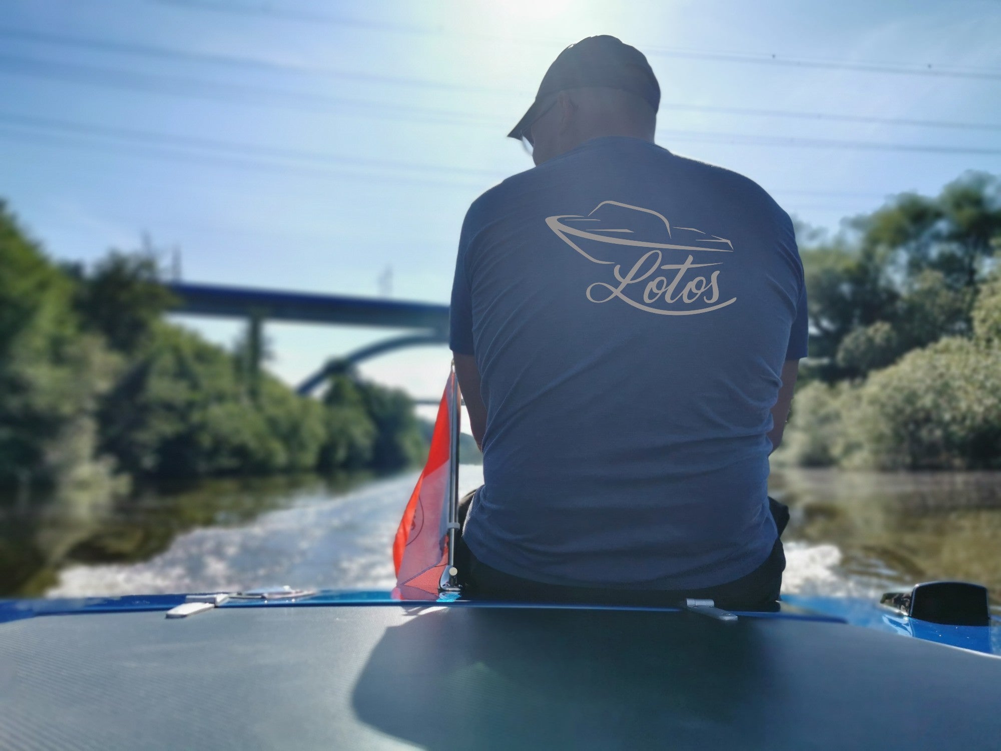 rhbs-shop.com. Lotos DDR Sportboot, Wartburg Ersatzteile. Rene Hahn sitzt auf einem Lotos und hat ein Shirt mit Lotos Logo in silber an.